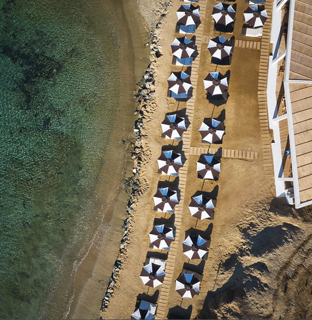 An overhead view of a stylish beach club with loungers, umbrellas, and Sun of a Beach towels.