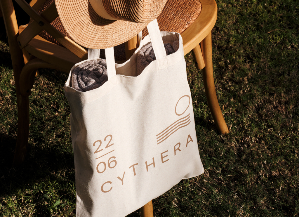 Wooden chair facing the sunset with a custom-made bag, two towels, and a hat, perfect for a beach or poolside event.