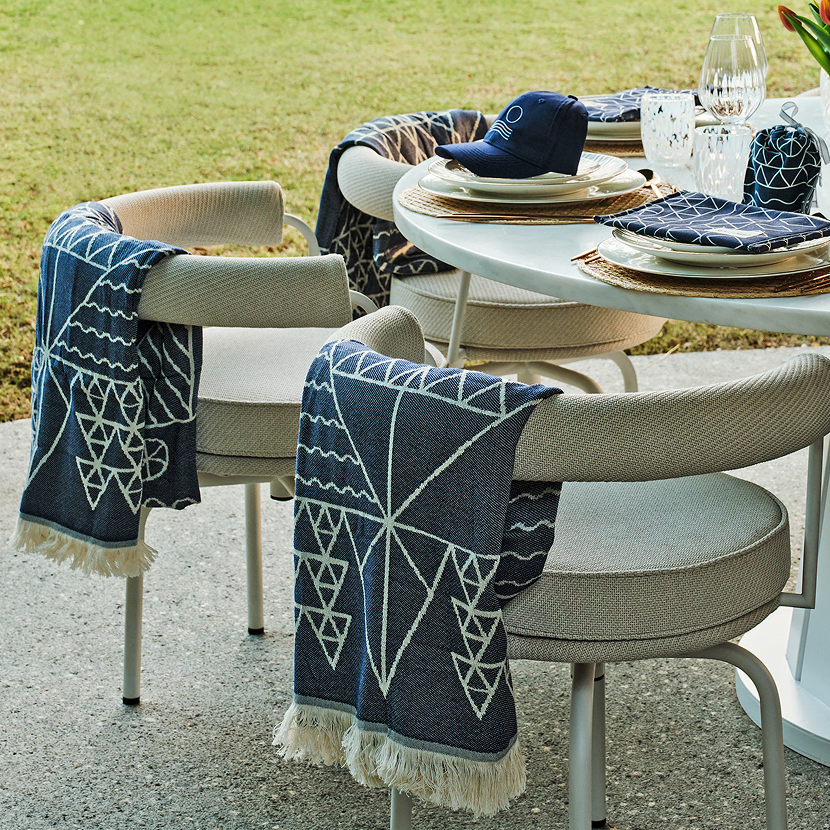 An elegant outdoor table setting featuring luxury towels draped over chairs and matching pouches placed on plates, perfect for high-end corporate special events.